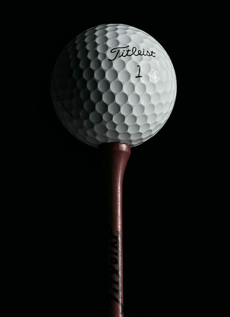 A golf ball on a golf tee against a black background