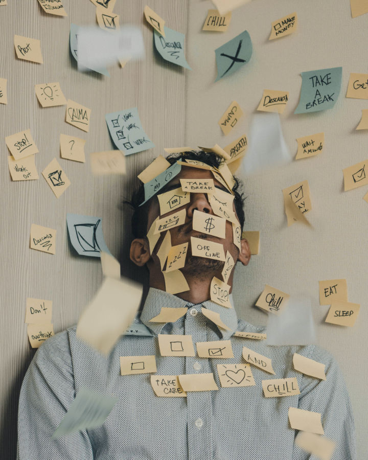 Man laying down with post it notes listing tasks covering him